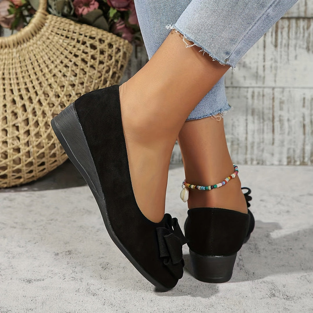 Stylish women's slip-on flats, featuring a comfortable wedge and cute bow.