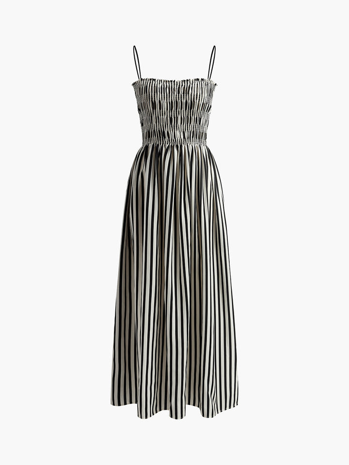 Woman wearing a flowing black pinstripe maxi dress with smocked top, a strappy summer dress for casual outings.