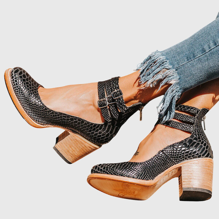 Women's bold buckle strap cutout ankle boots with block heel. Stylish, western-inspired fashion footwear.