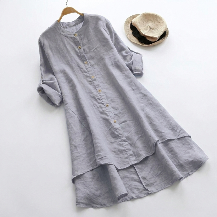 Close-up of women's button-down shirt dress, showing layered hem & long sleeves. Comfortable midi, ideal for all seasons.
