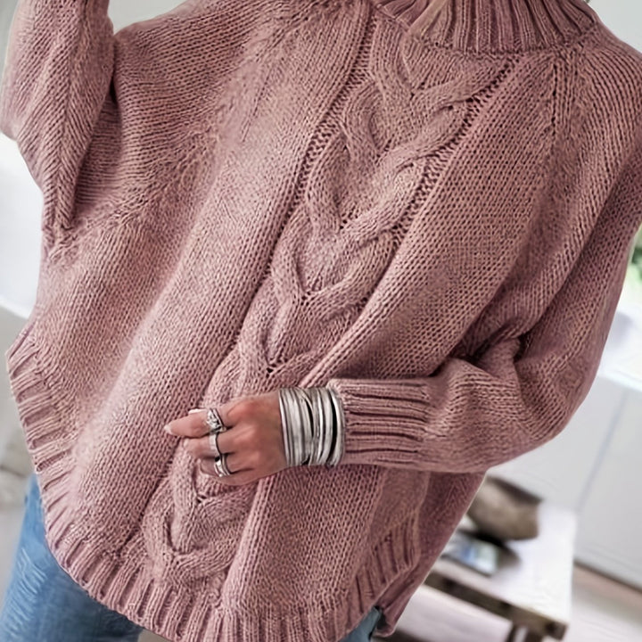 Women's warm cable knit sweater with a cozy high neck and unique flared hem, suitable for winter days.