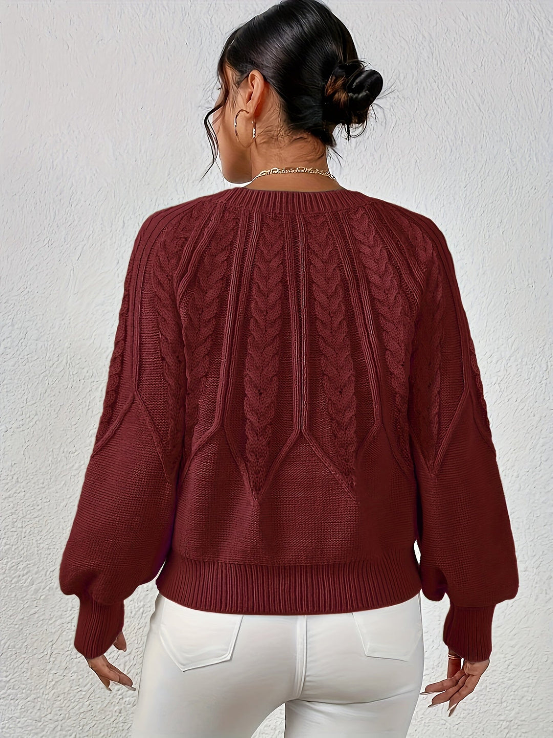 Back view of women's cable knit sweater, relaxed fit, showcasing lantern sleeves.