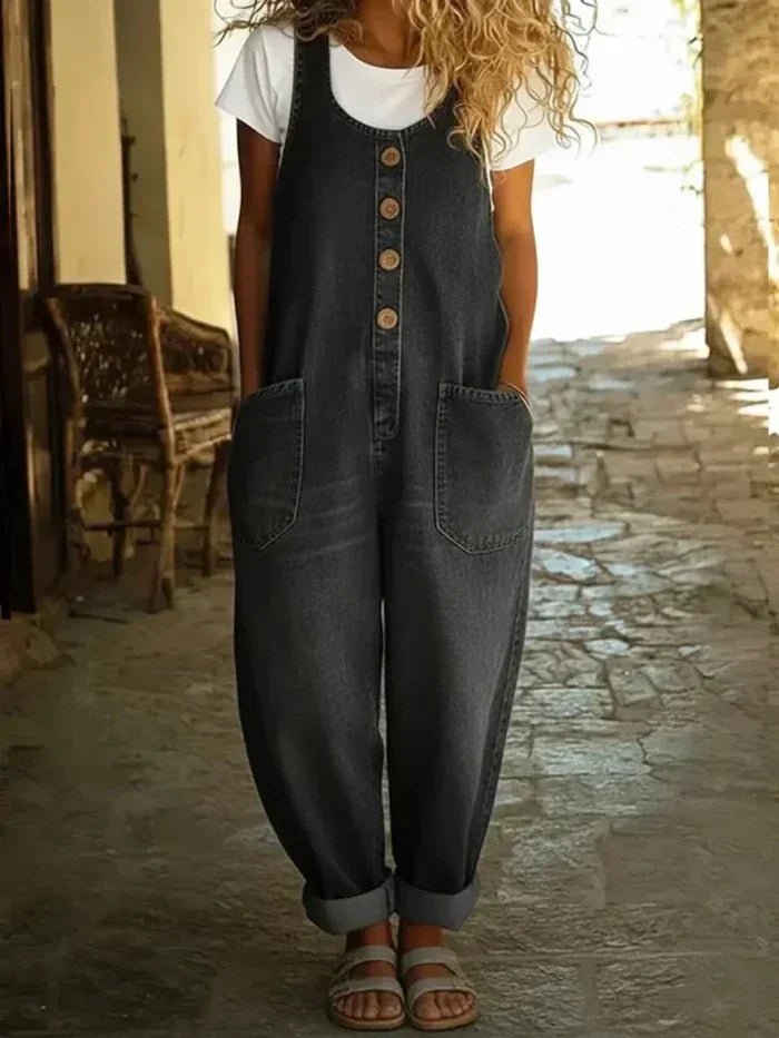 Comfortable women's denim jumpsuit featuring a scoop neck, sleeveless, loose fit, and tapered leg. Casual spring outfit.