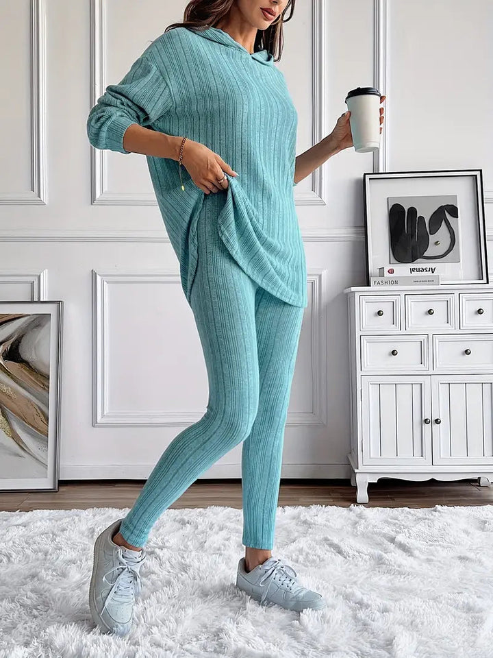 Woman relaxing in a grey ribbed knit loungewear set, featuring hoodie and matching leggings
