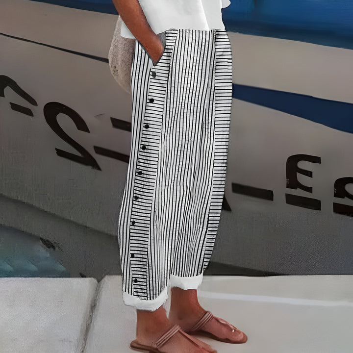 Close-up of women's cropped straight-leg trousers, highlighting stripe panel detail & decorative button accents.