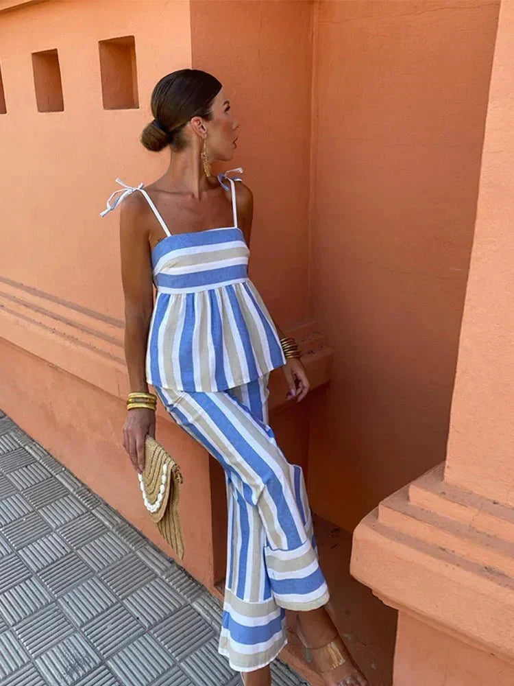 Fashionable women's striped peplum top and matching wide-leg trousers outfit, ideal for vacation wear.