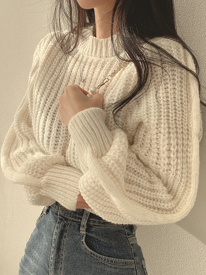 Woman wearing a cozy chunky knit lantern sleeve sweater, styled for a casual yet chic winter look
