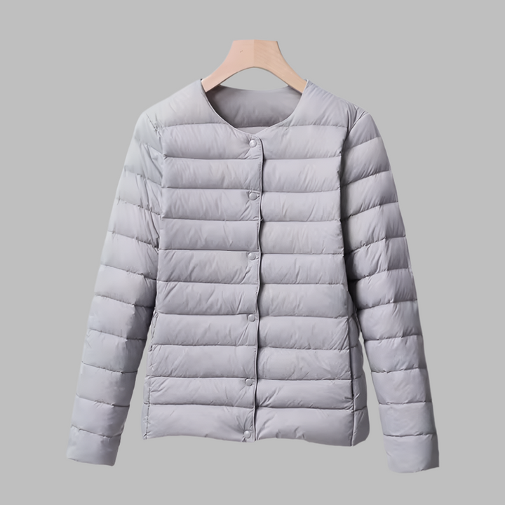 Stylish women's ultralight puffer jacket, collarless for easy layering, in a versatile gray, perfect travel companion.