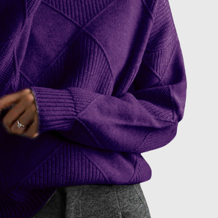 Woman wearing an oversized cozy roll neck sweater with diagonal seam, elegant winter fashion.