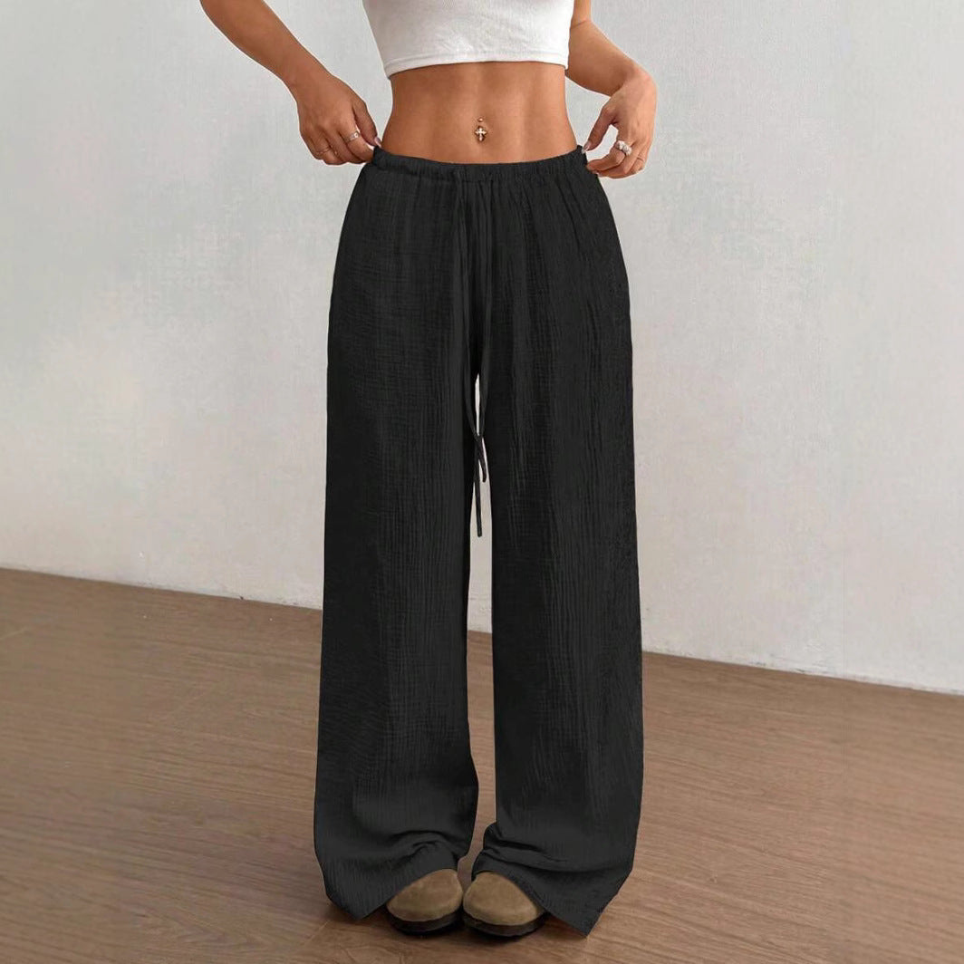 Full length view of women's crinkle wide leg pants, showcasing flowy fabric & drawstring waist detail.