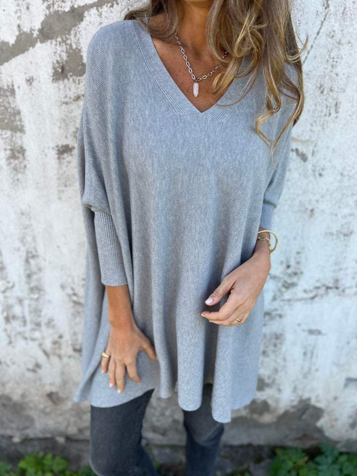Woman wearing a comfortable V-neck swing tunic sweater with batwing sleeves for a relaxed, everyday fall look.