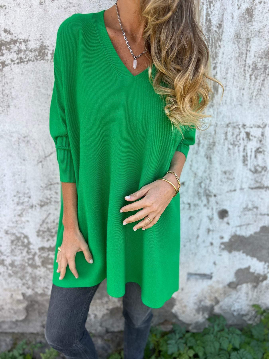 Detail of a women's relaxed fit V-neck pullover sweater, highlighting its trendy batwing sleeves and soft texture.