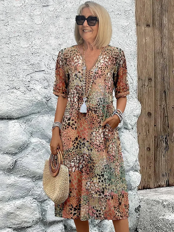 Full length view of a woman wearing a vibrant floral printed V-neck midi dress. Elegant A-line silhouette.
