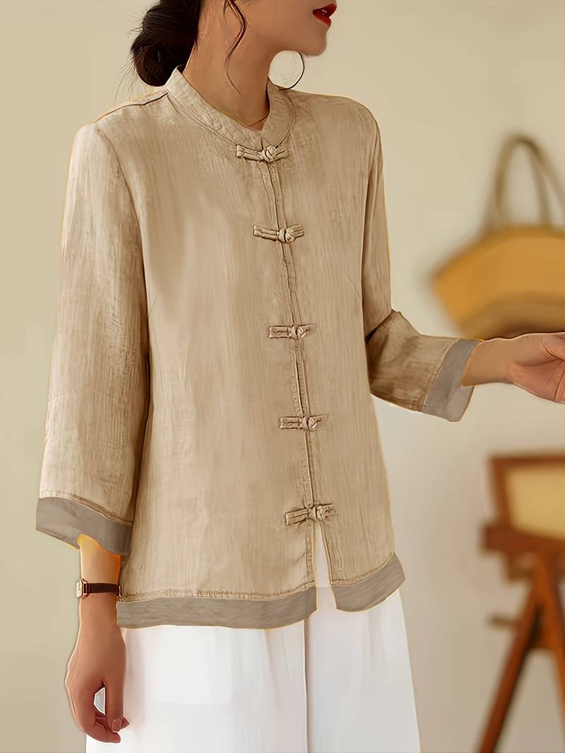 Fashionable women's blouse with mandarin collar, frog button details, and comfortable three-quarter sleeves.