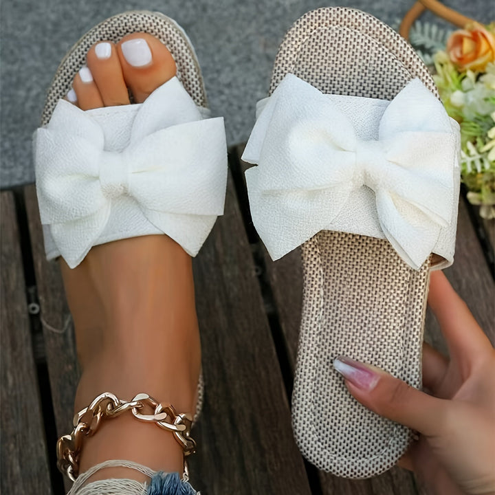 Chic women's pearl bow slide sandals for summer. Comfortable, casual slip-on flats, ideal for vacation and everyday style.