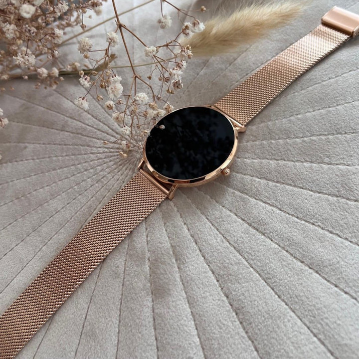 Woman wearing a rose gold elegant slim smartwatch, tracking daily activity. Stylish wearable tech.