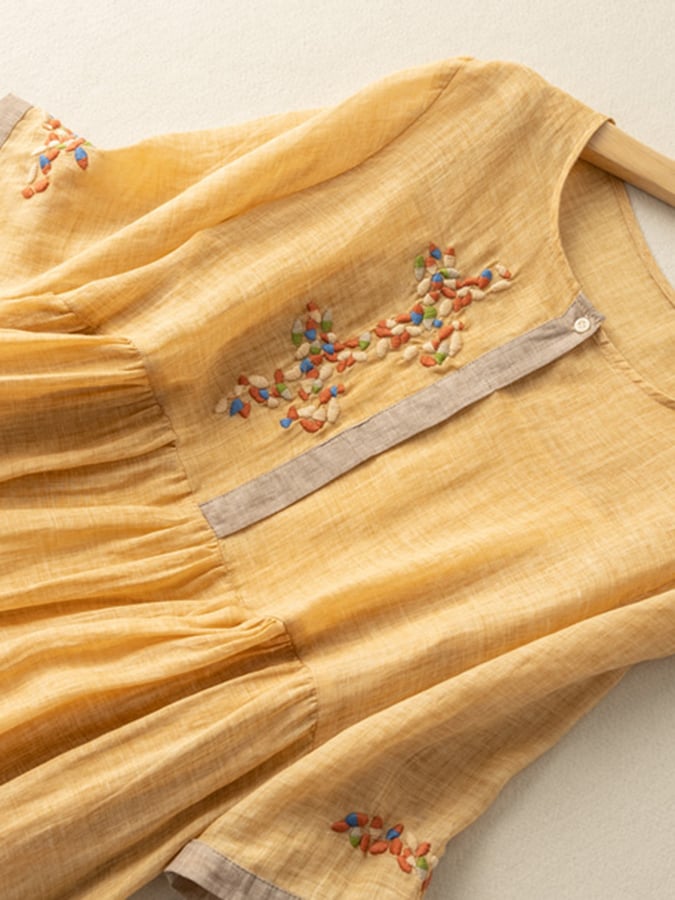Close-up of intricate embroidery on a women's boho midi dress. Highlights elegant details & round neck.