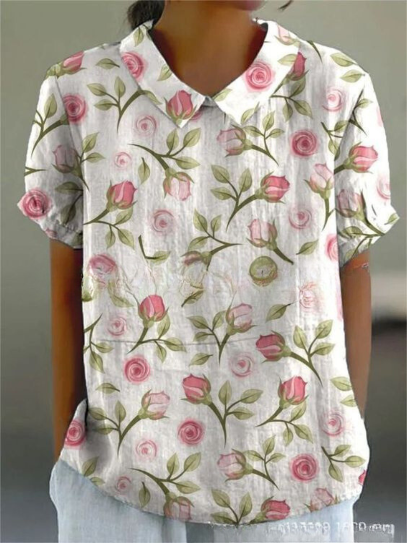 Close-up of women's short sleeve blouse showcasing intricate floral vine embroidery and Peter Pan collar.