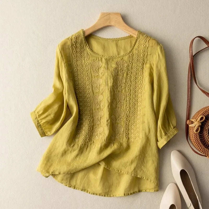 Close-up of a women's floral embroidered puff sleeve blouse, showcasing the detailed stitching and flowy high-low hem.