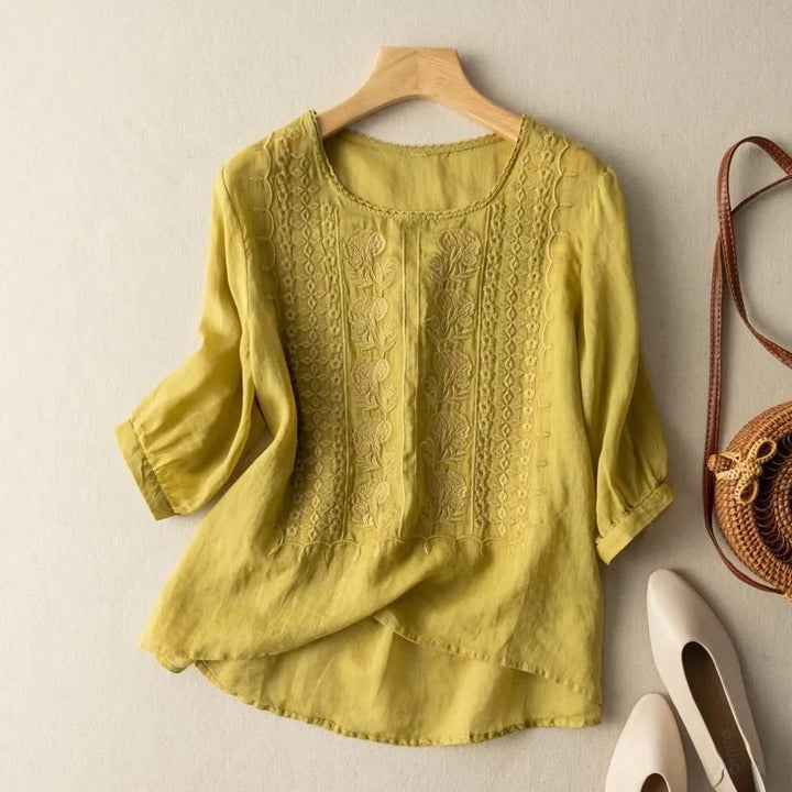 Close-up of a women's floral embroidered puff sleeve blouse, showcasing the detailed stitching and flowy high-low hem.