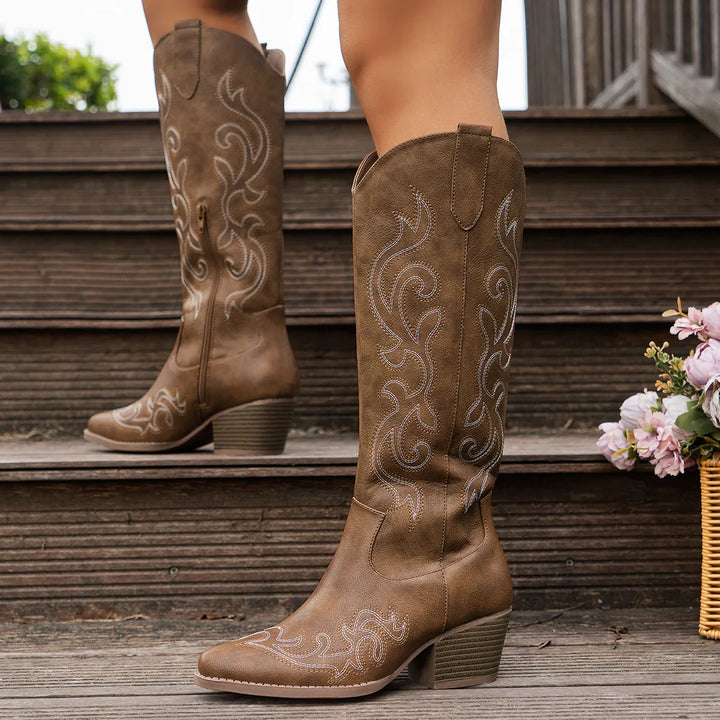 Close-up of the pointed toe and block heel on women's embroidered Western ankle boots, highlighting texture