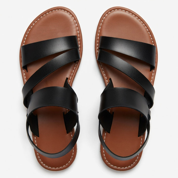 Stylish slip-on women's flat sandals with crossover straps, perfect for warm weather fashion.