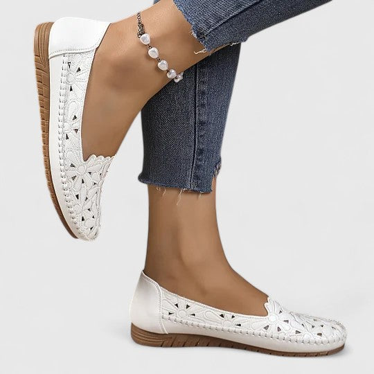 Woman wearing comfortable perforated floral cutout slip-on ballet flats. Perfect for casual everyday spring elegance.