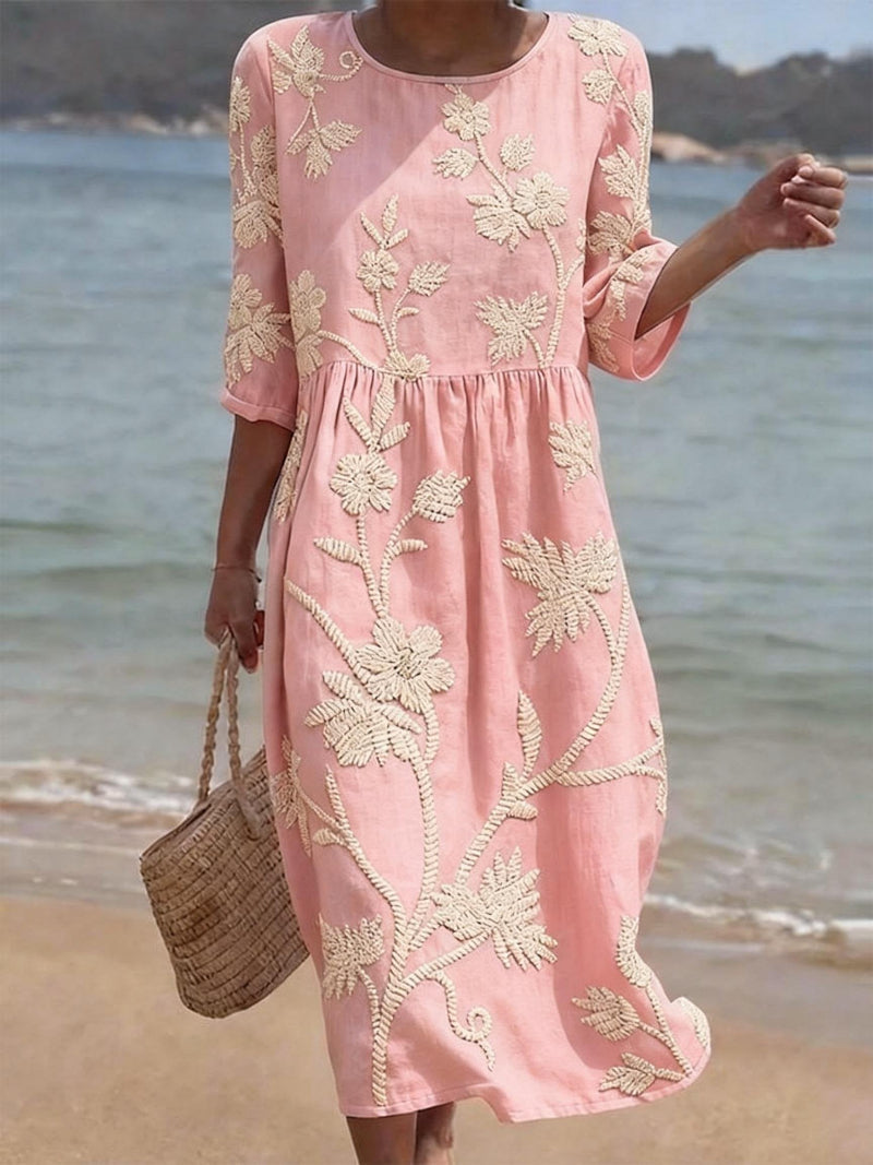 Close-up of the delicate floral embroidery on a women's elegant flowing maxi dress with three-quarter sleeves.