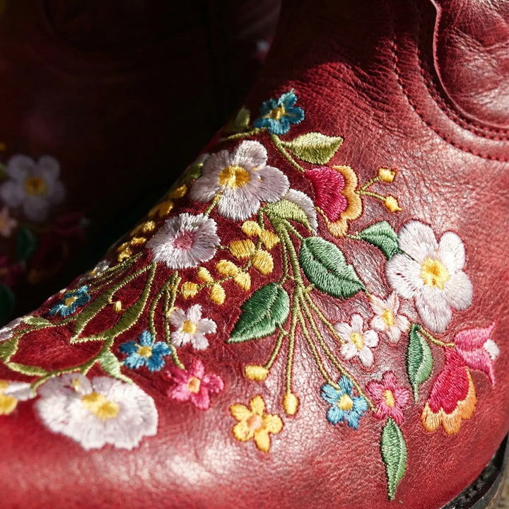 Close-up of intricate floral embroidery detail on women's stylish western ankle boots with pull-on design.