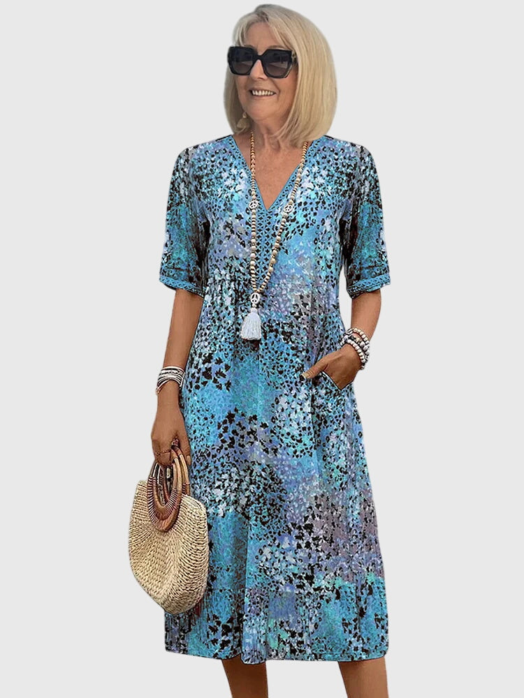 Casual women's flowy midi dress with a stylish v-neck, abstract print, flutter sleeves, and practical pockets.