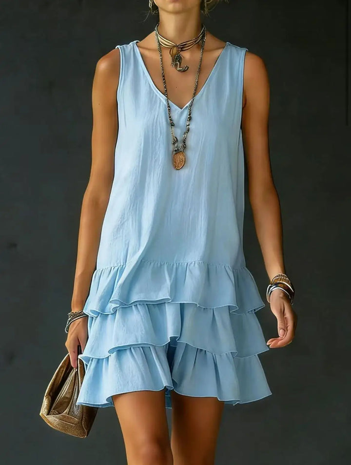 Elegant women's sleeveless V-neck tiered mini dress with ruffle details. Flowy fabric, perfect for summer vacation style.