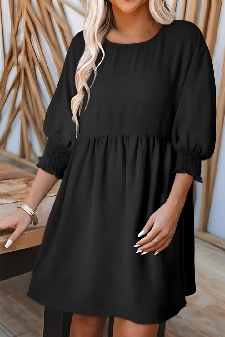 Half sleeve babydoll mini dress featuring elegant smocked cuffs and a flowy tiered skirt.