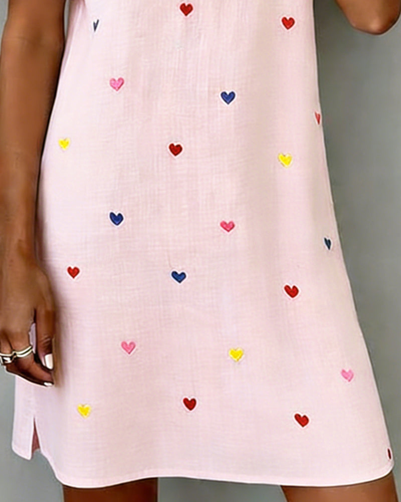 Close-up of women's heart print V-neck mini dress. Highlights puff sleeves & relaxed fit for casual wear.