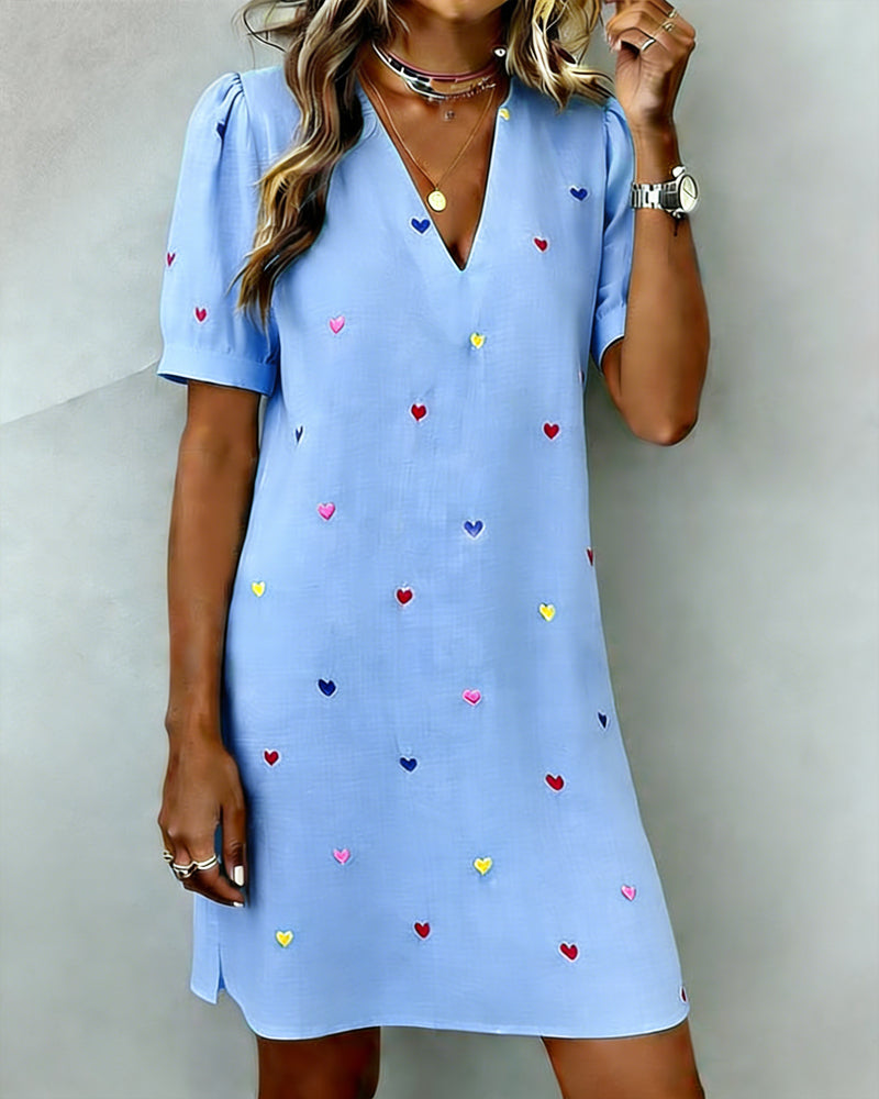 Woman models a trendy heart print V-neck puff sleeve casual mini dress. Perfect for everyday fashion & vacation.