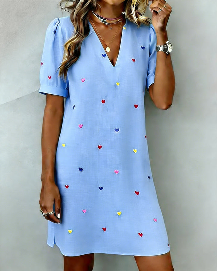 Woman models a trendy heart print V-neck puff sleeve casual mini dress. Perfect for everyday fashion & vacation.