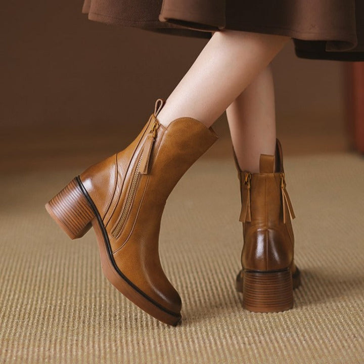 Close-up of women's high heel ankle boots showing decorative metal zipper & sleek design.