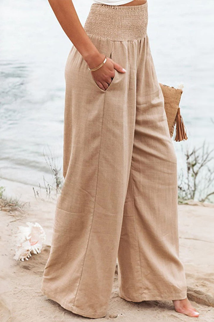 Flowing linen wide-leg pants with a high smocked waist, perfect for comfortable summer wear.