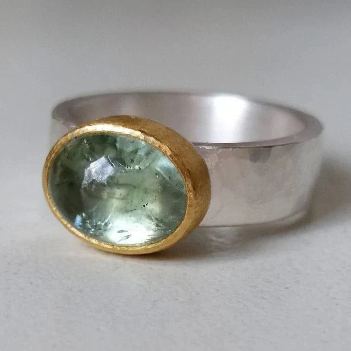 Women's oval aquamarine gemstone ring with gold bezel and sterling silver band. Mixed metal jewelry.