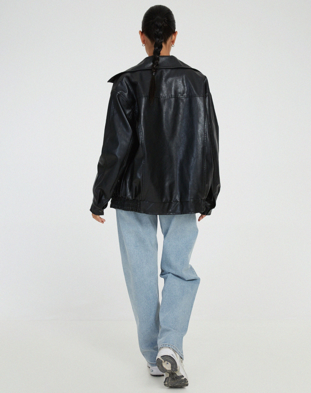 Back view of a women's brown oversized faux leather bomber jacket, emphasizing its relaxed and chic silhouette.