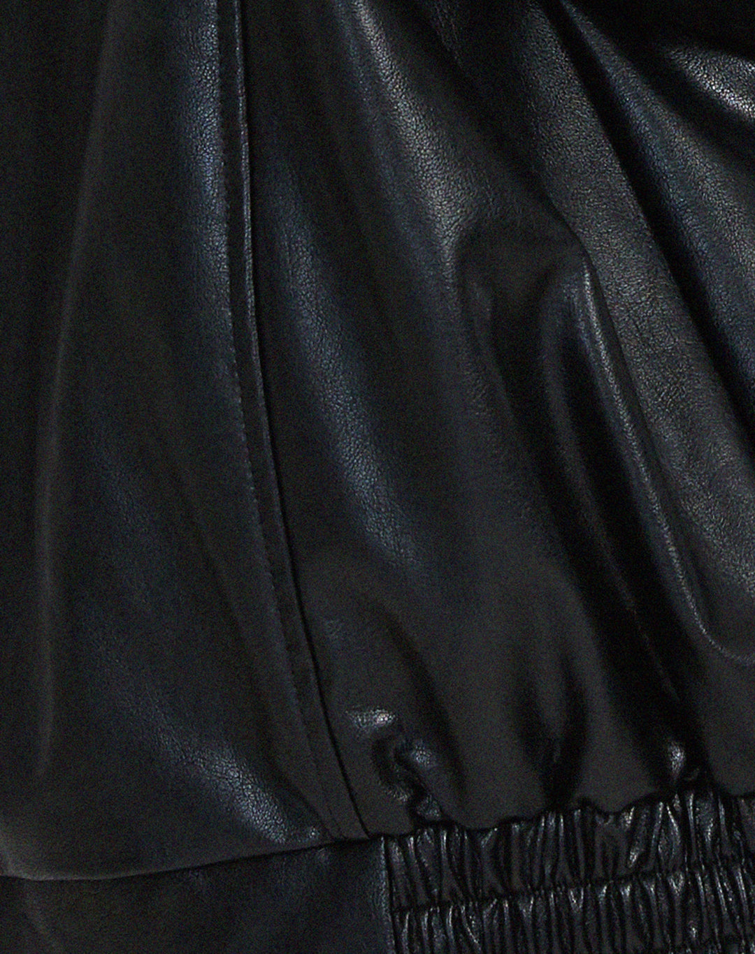 Side profile of a woman wearing an oversized brown faux leather bomber jacket, ideal for layering.