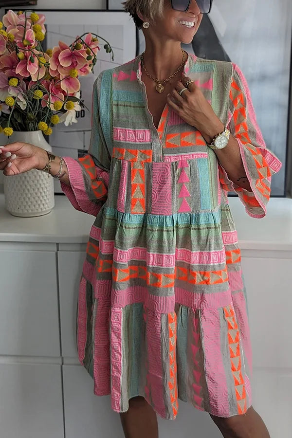 Feminine tiered mini spring dress with a V-neck & 3/4 sleeves, ideal for casual day wear. Features a playful print.