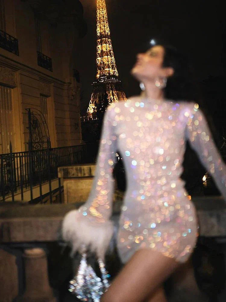 Fashionable women's mini dress, sheer sequin design with dramatic feather cuffs & long sleeves.
