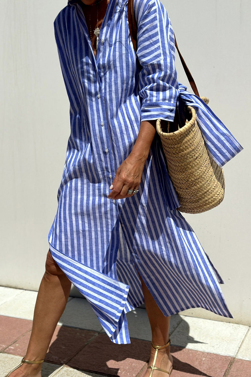 Full shot of a model wearing a relaxed fit striped midi dress with collar and button-down front, perfect for summer.