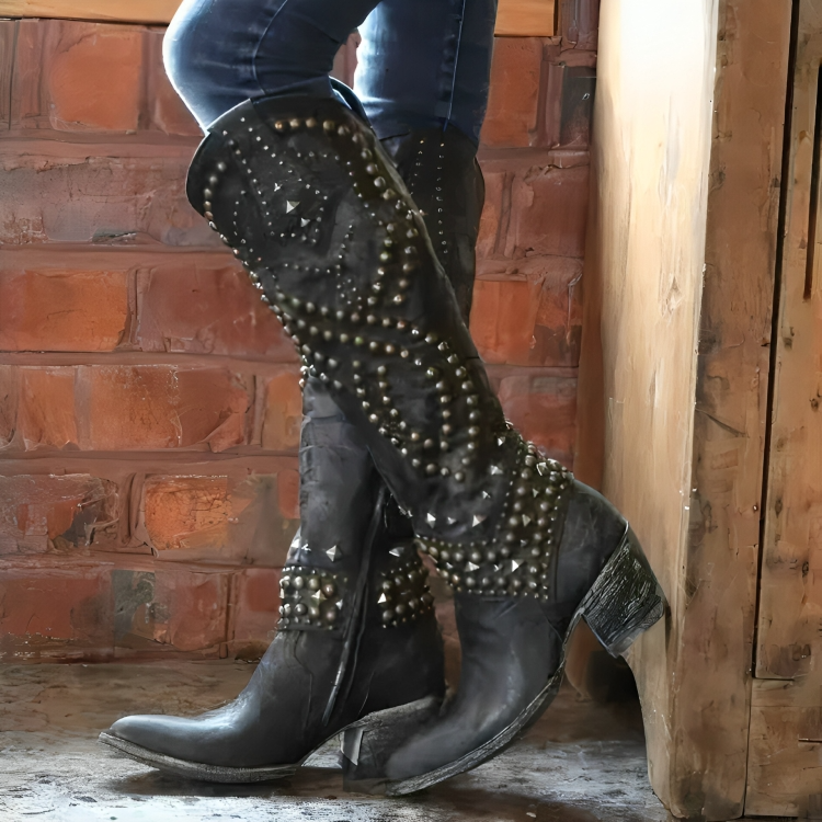 Brown women's studded western boots, knee-high design with metal studs. A chic and edgy choice for fashion-forward looks.