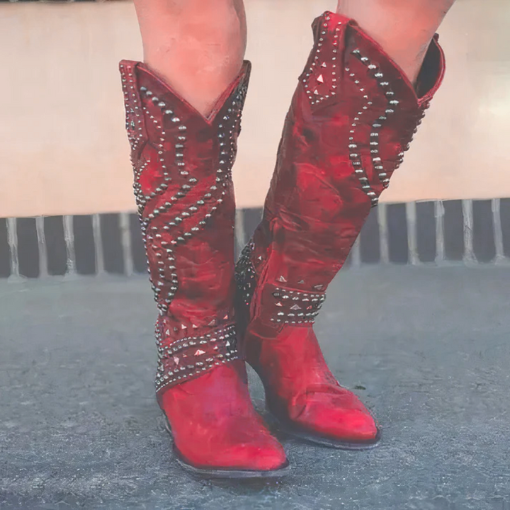 Vibrant red studded knee-high cowboy boots for women. Durable Western footwear, perfect for bold style and comfort.