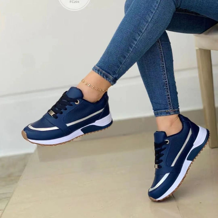 Close-up of women's fashion platform sneakers with elegant gold trim and classic lace-up design.