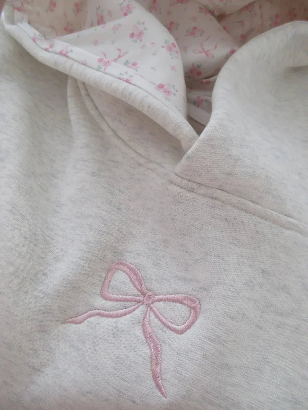 Cozy women's hoodie featuring a relaxed fit, chic bow detail, and practical kangaroo pocket. Ideal for winter essentials.