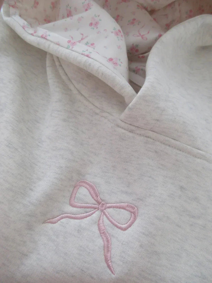 Cozy women's hoodie featuring a relaxed fit, chic bow detail, and practical kangaroo pocket. Ideal for winter essentials.