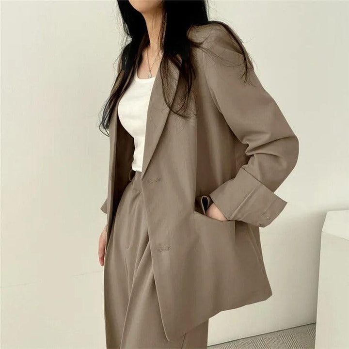 Empowering women's suit with a long tailored blazer and matching trousers, perfect for boardrooms.