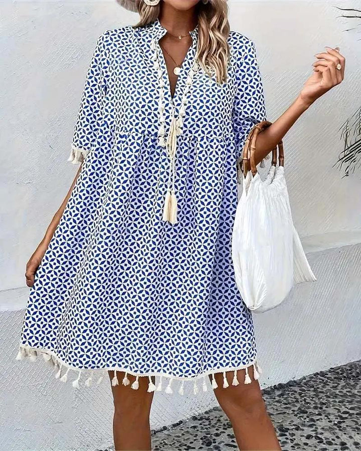 Printed V-neck women's mini dress with stylish tassel trim & short sleeves. Perfect for spring/summer fashion.